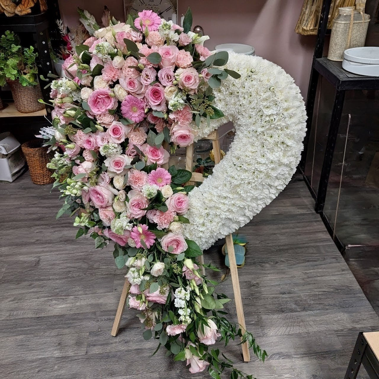 Floral arrangement with pink and white flowers on a wooden stand.